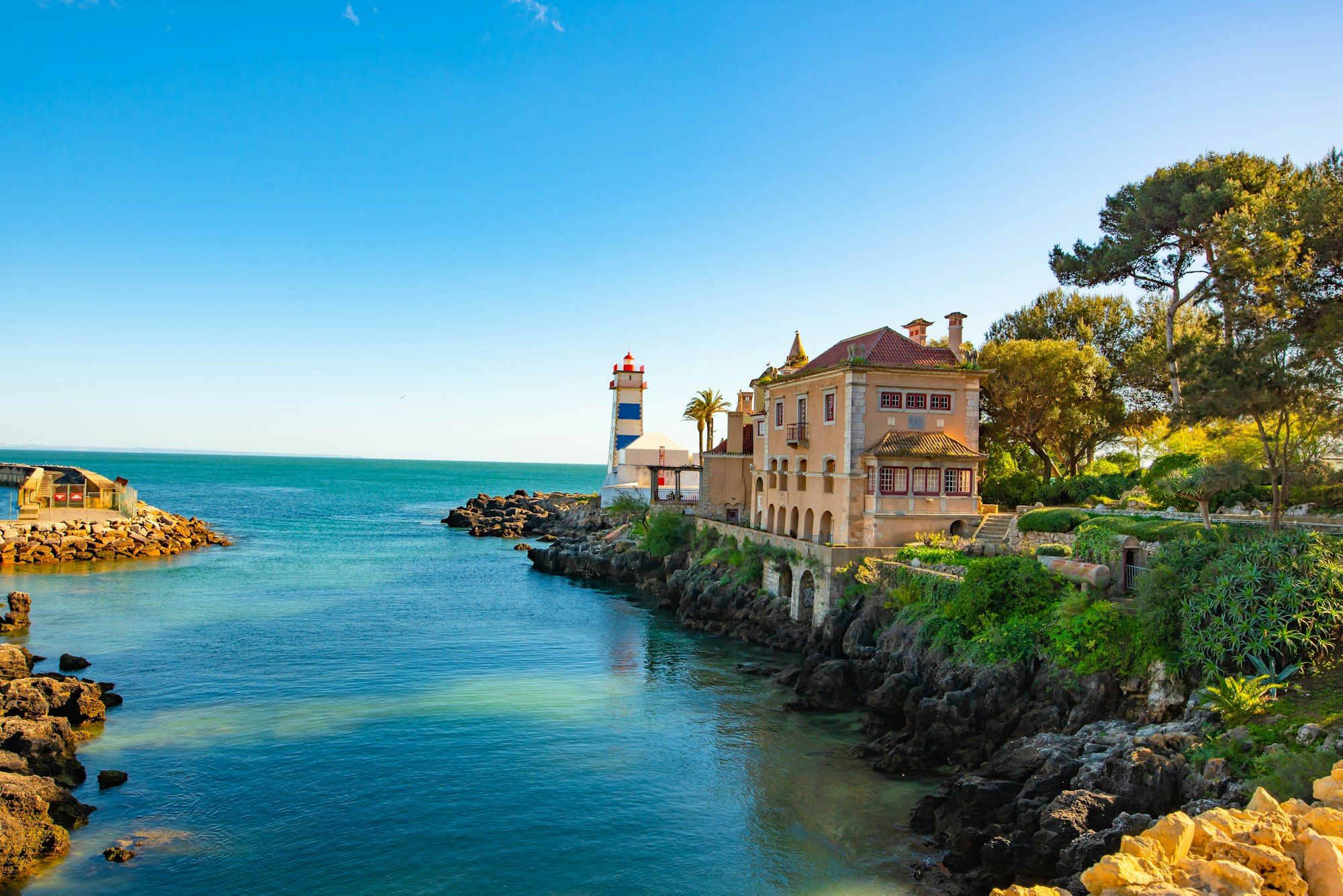 The lighthouse and rocky bay at Cascais under a blue sky