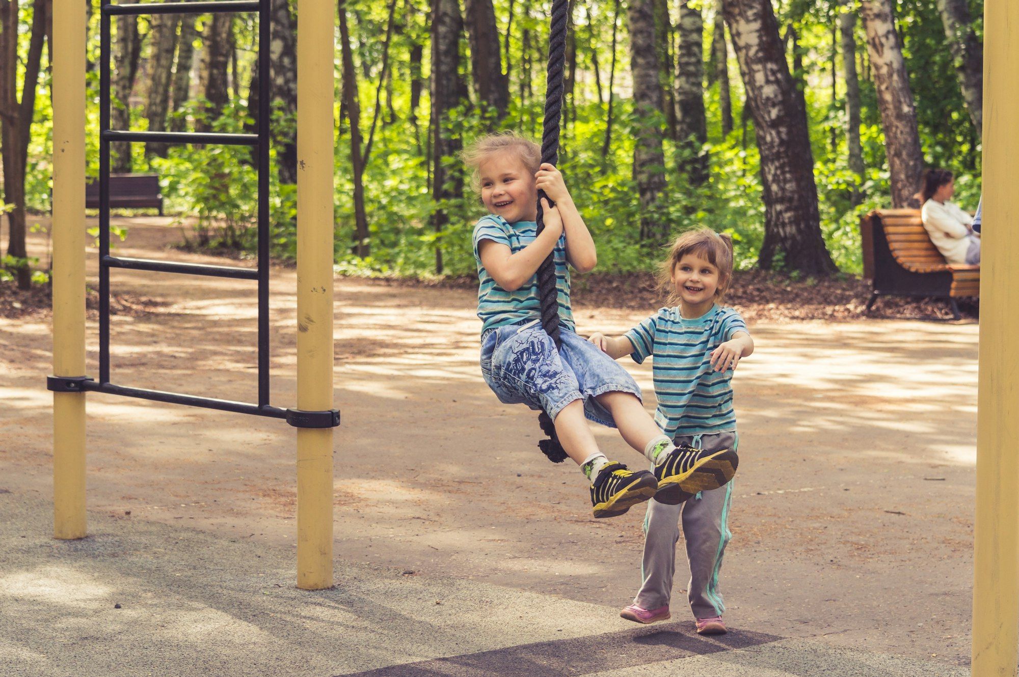 Two children on a swing in a park