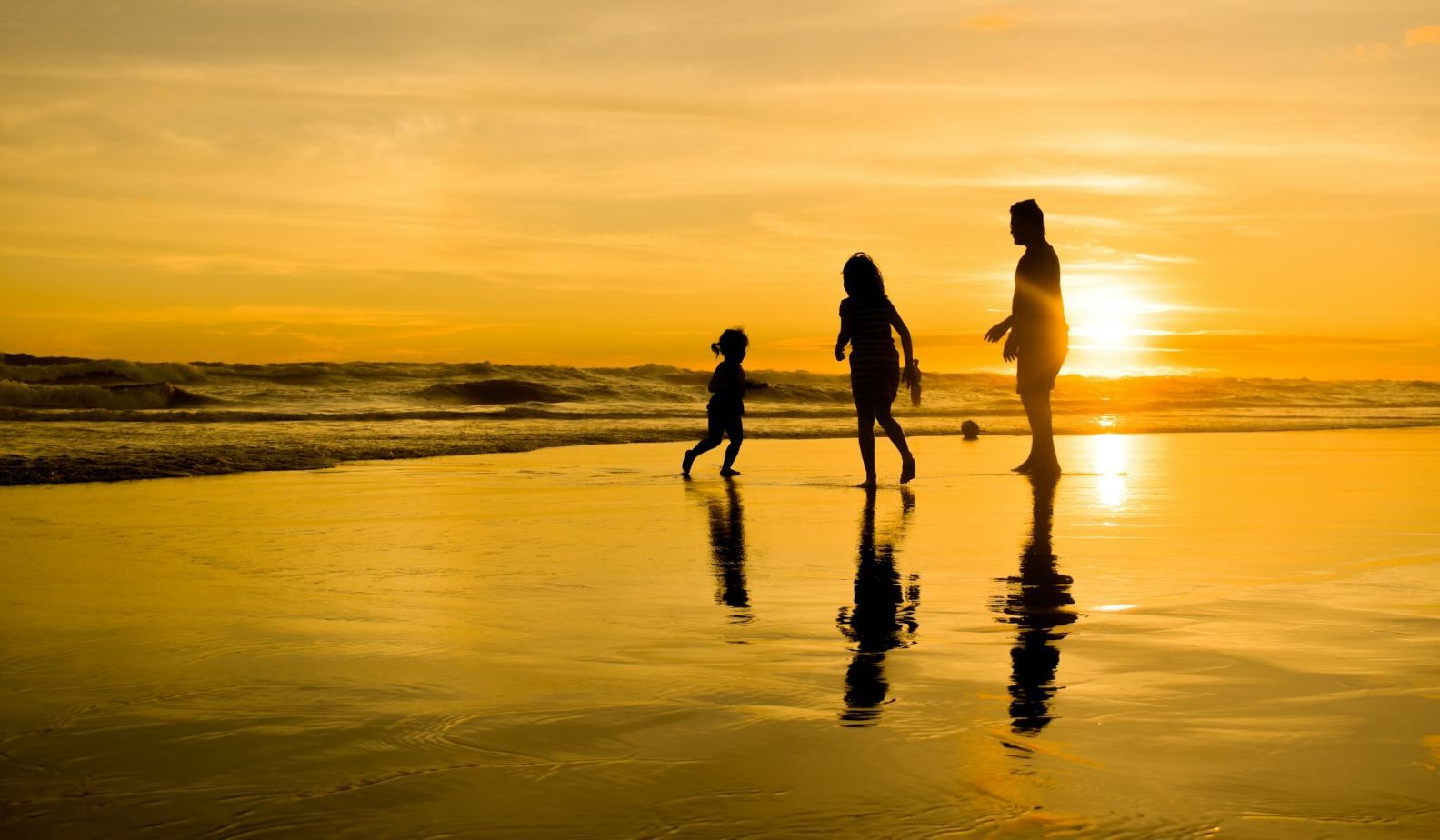 A family walking along the beach at sunset